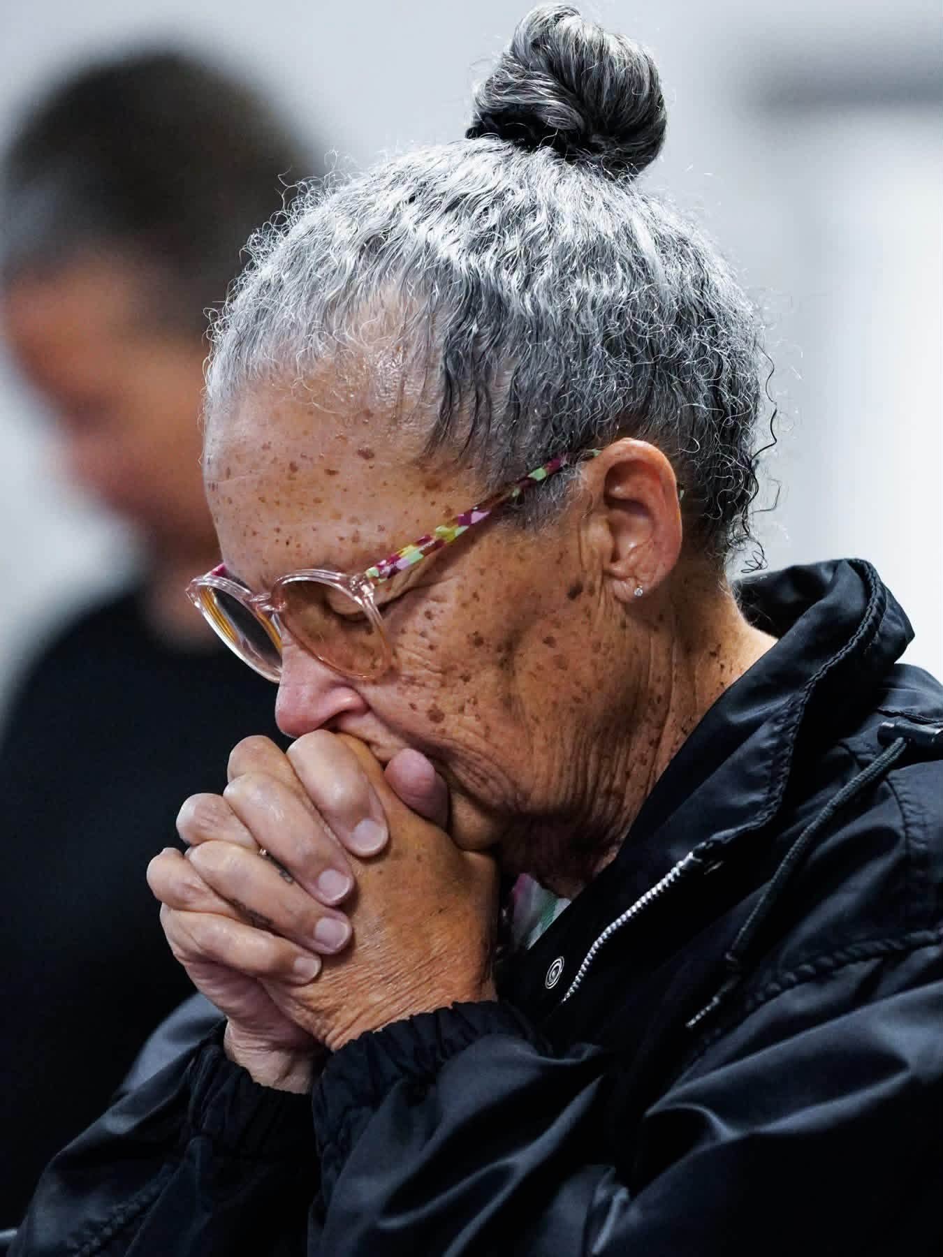 A woman praying quietly with her hands clasped
