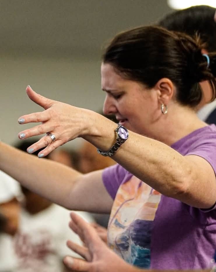 A woman reaching forward in prayer