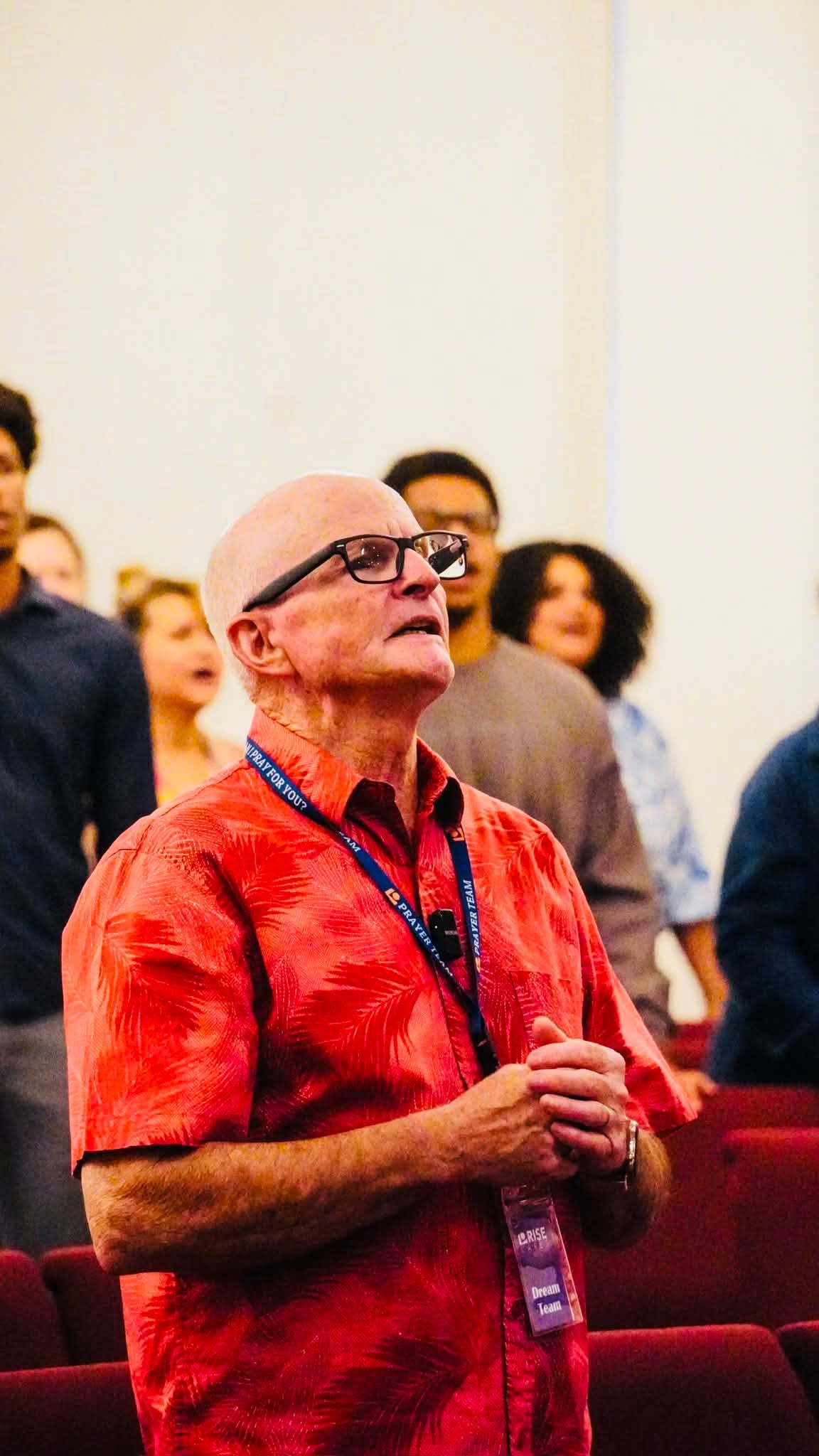 A worshipper in an orange shirt with his face lifted